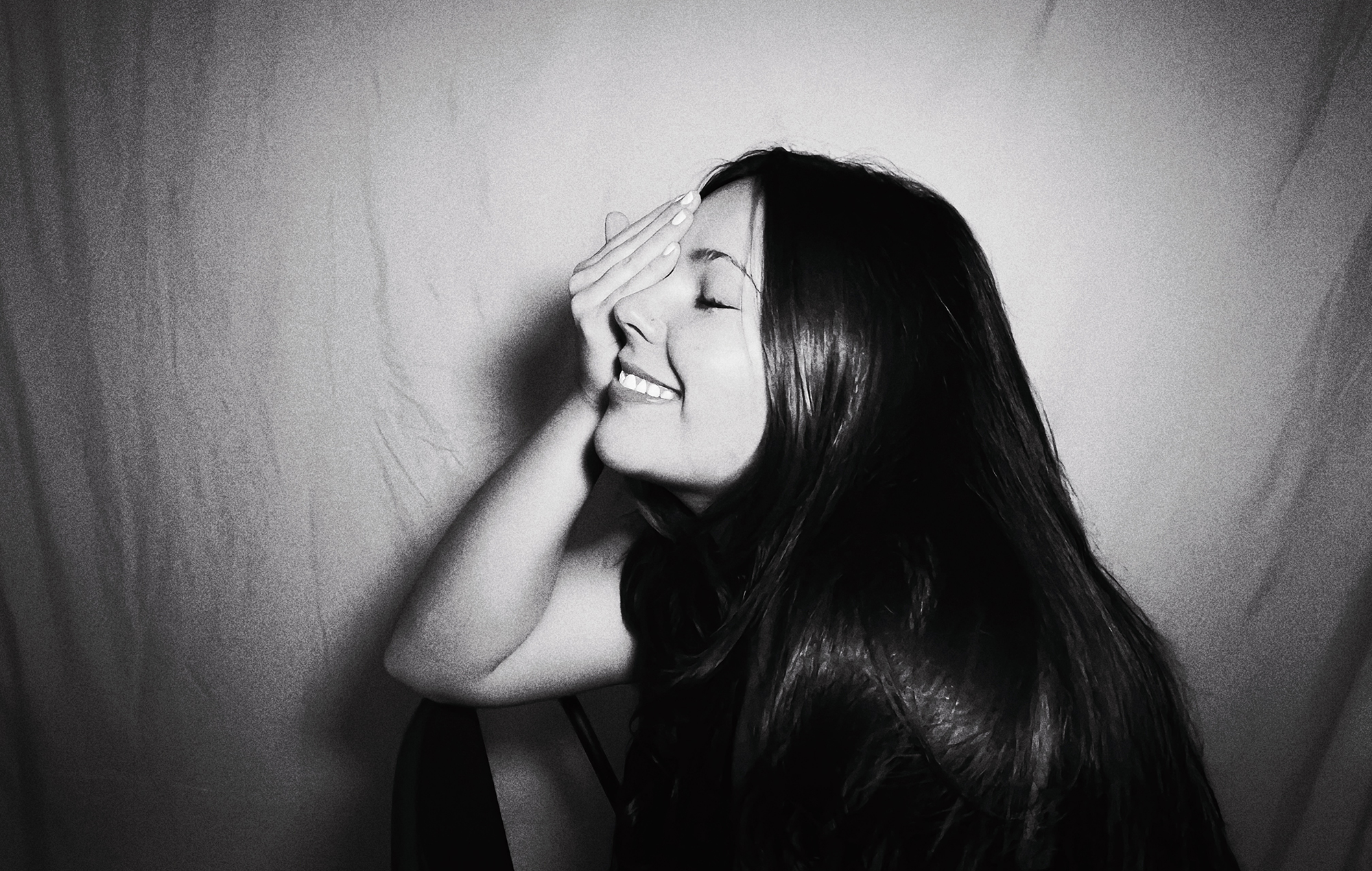 Gigi Perez photographed in black and white with her hand covering her face, photo by press