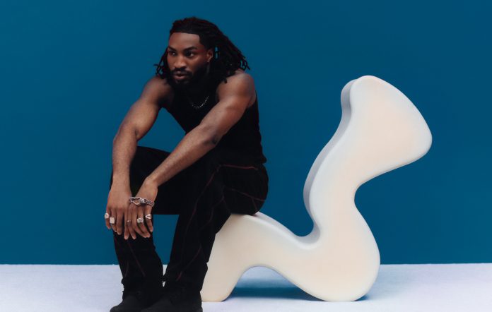 Odeal photographed seated on a wavy white chair, photo by Elliot Hensford